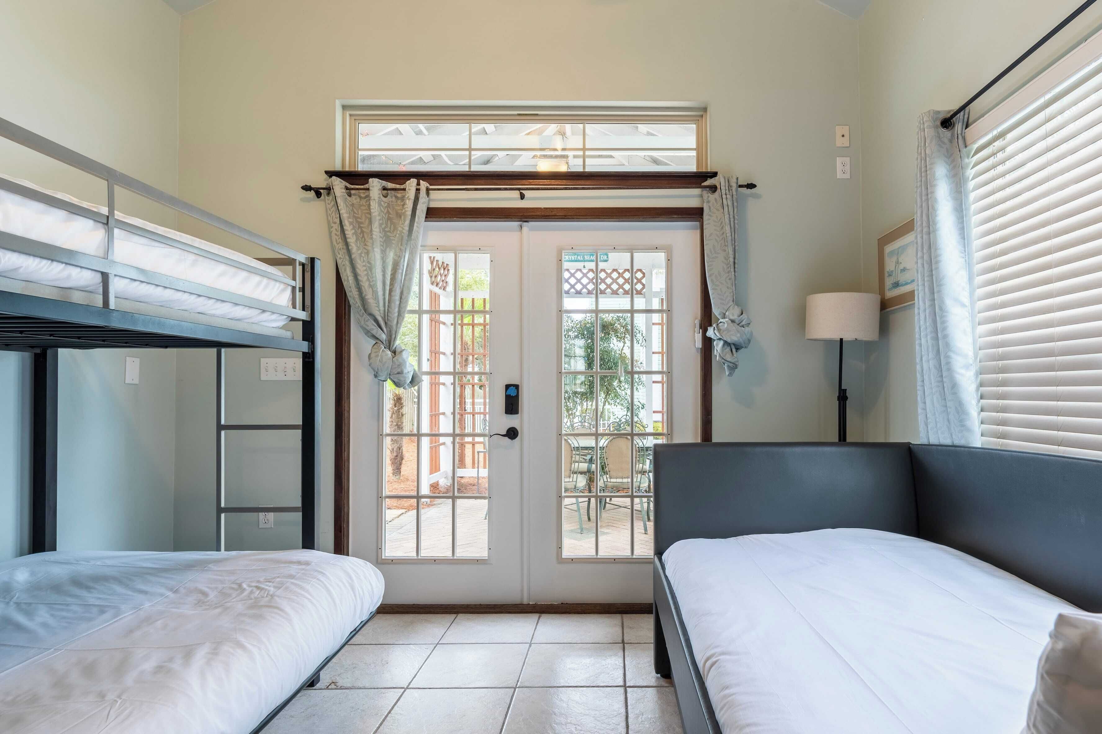 Una habitación con literas, un escritorio, una silla y un ventanal con cortinas.
