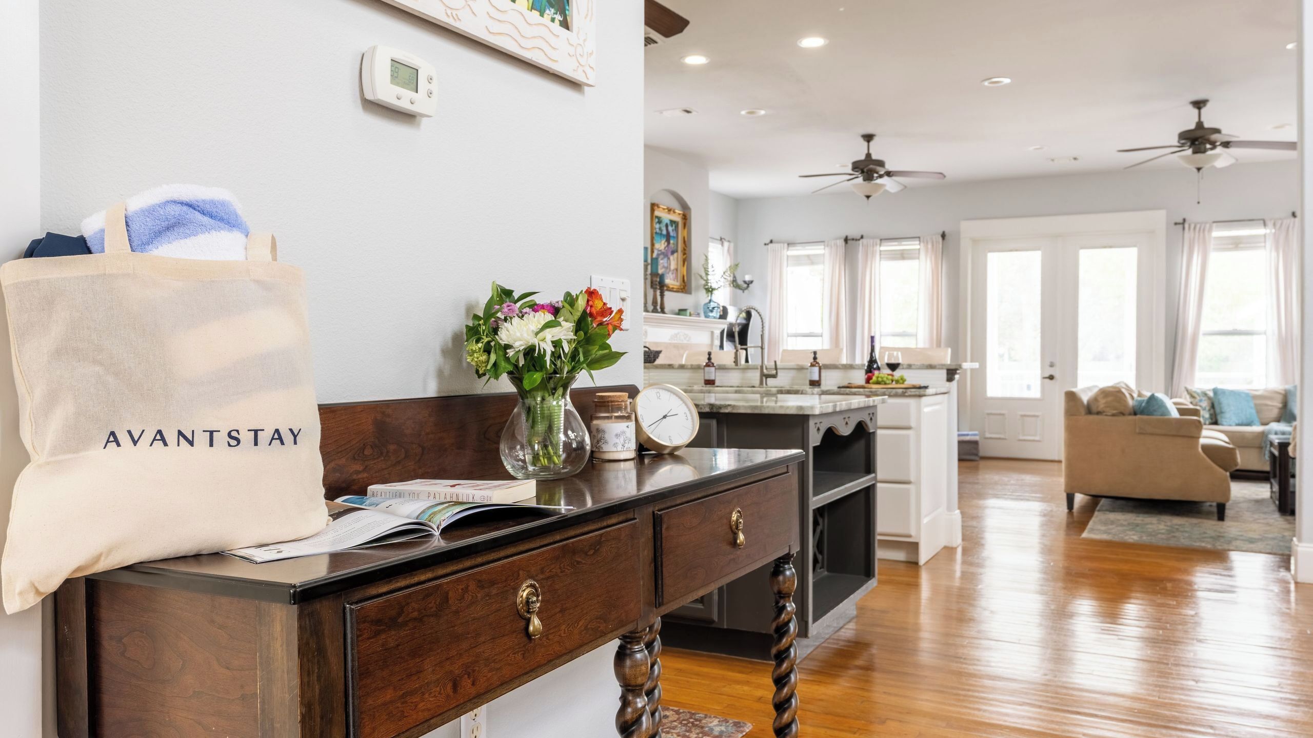 A modern kitchen with wooden cabinetry, a central island, and a dining area with a sofa.