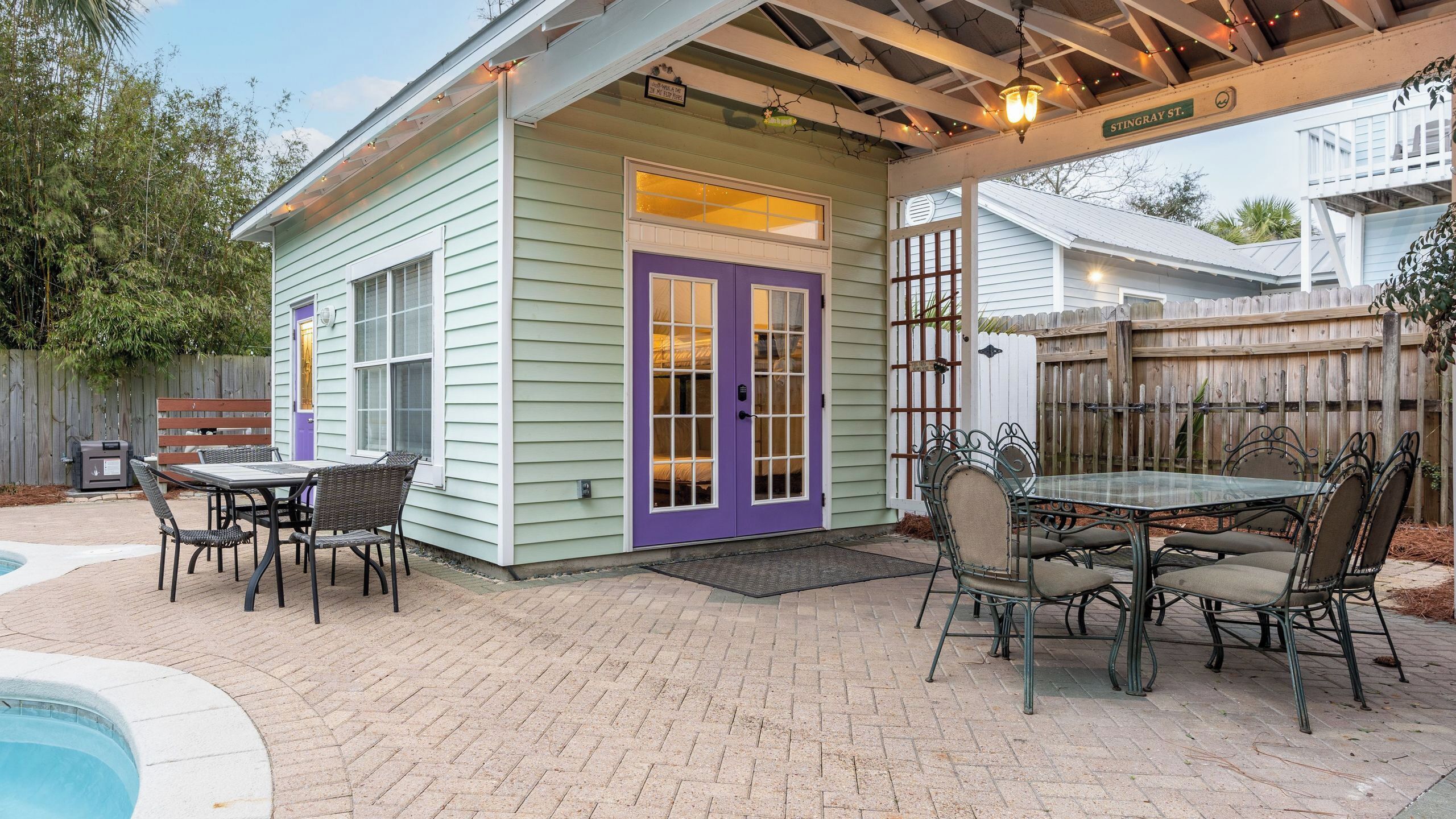 A small house with a covered patio, a pool, and outdoor furniture.
