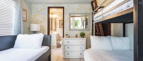 A bedroom with two beds, a wooden ceiling, a small dresser, and a mirror.
