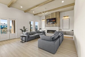 Ein modernes Wohnzimmer mit einer Eckcouch, einem Kamin und einem an der Wand montierten Fernseher.