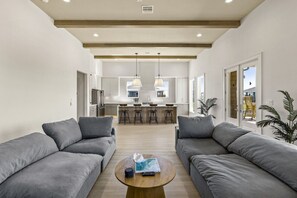 Ein modernes Wohnzimmer mit grauen Sofas, einem Couchtisch und einer Küche im Hintergrund.
