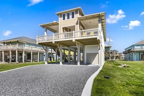A multi-story house with a covered porch, a garage, and a well-maintained lawn.