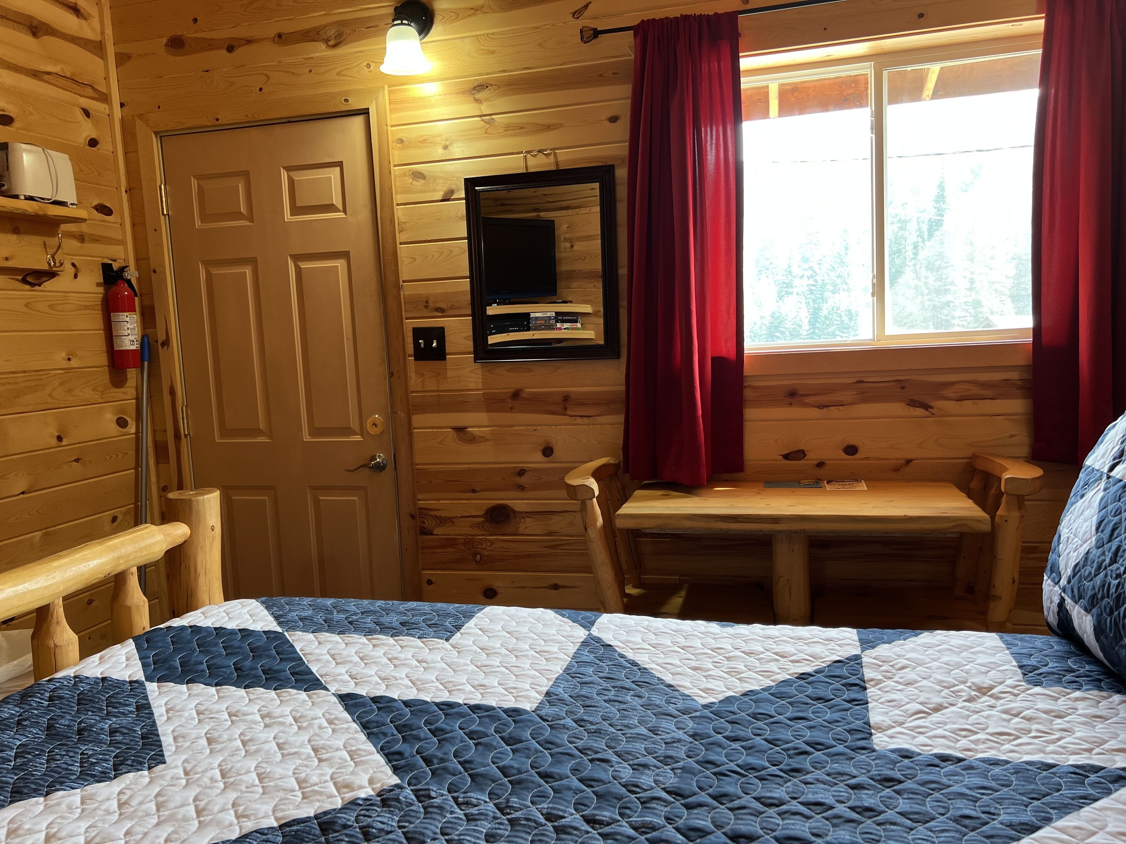 Una habitación de cabaña de madera con una cama, una mesa y una silla.