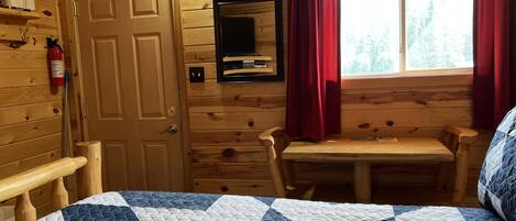 Una habitación de cabaña de madera con una cama, una mesa y una silla.