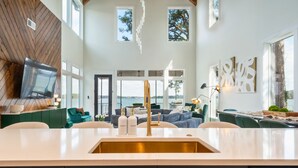 Eine moderne Küche mit einer zentralen Kochinsel, ein Essbereich mit Blick und ein Wohnzimmer mit Kamin.
