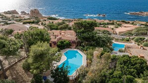 A coastal resort with multiple swimming pools, terraced houses, and rocky outcrops.