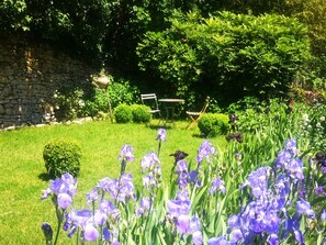 A garden with purple flowers, a stone wall, and a bench. - Lovely, luxuriously decorated house, intimate garden in a historic village (Le Buisson-de-Cadouin)