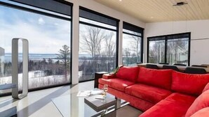A modern living room with a red sofa, large windows, and a glass coffee table.