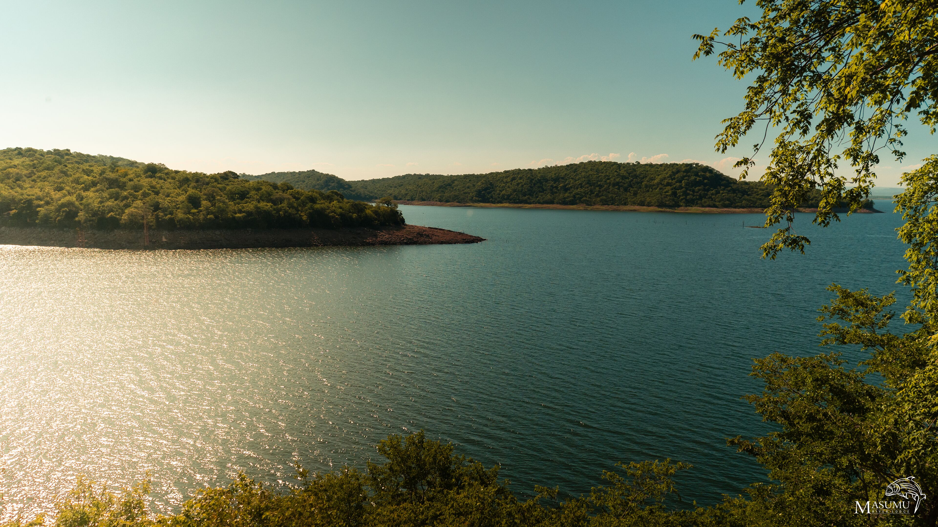 Un lago tranquilo rodeado de exuberante vegetación y colinas.