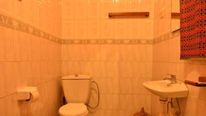 A small bathroom with a toilet, sink, and a decorative item on the floor. - Room in B&B - Amahoro Guest House - Queen Room (Muhoza)