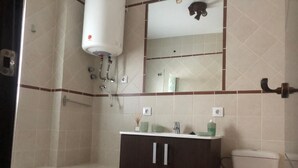 A bathroom with a bathtub, a toilet, a sink with a mirror above it, and a towel rack.