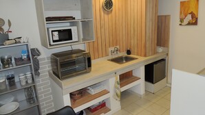 Uma cozinha compacta com micro-ondas, torradeira, pia e painéis de parede de madeira.