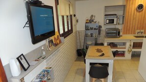 Cozinha compacta com televisão, micro-ondas e torradeira.