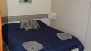 Um quarto com uma cama, um quadro na parede e uma mesa de cabeceira.