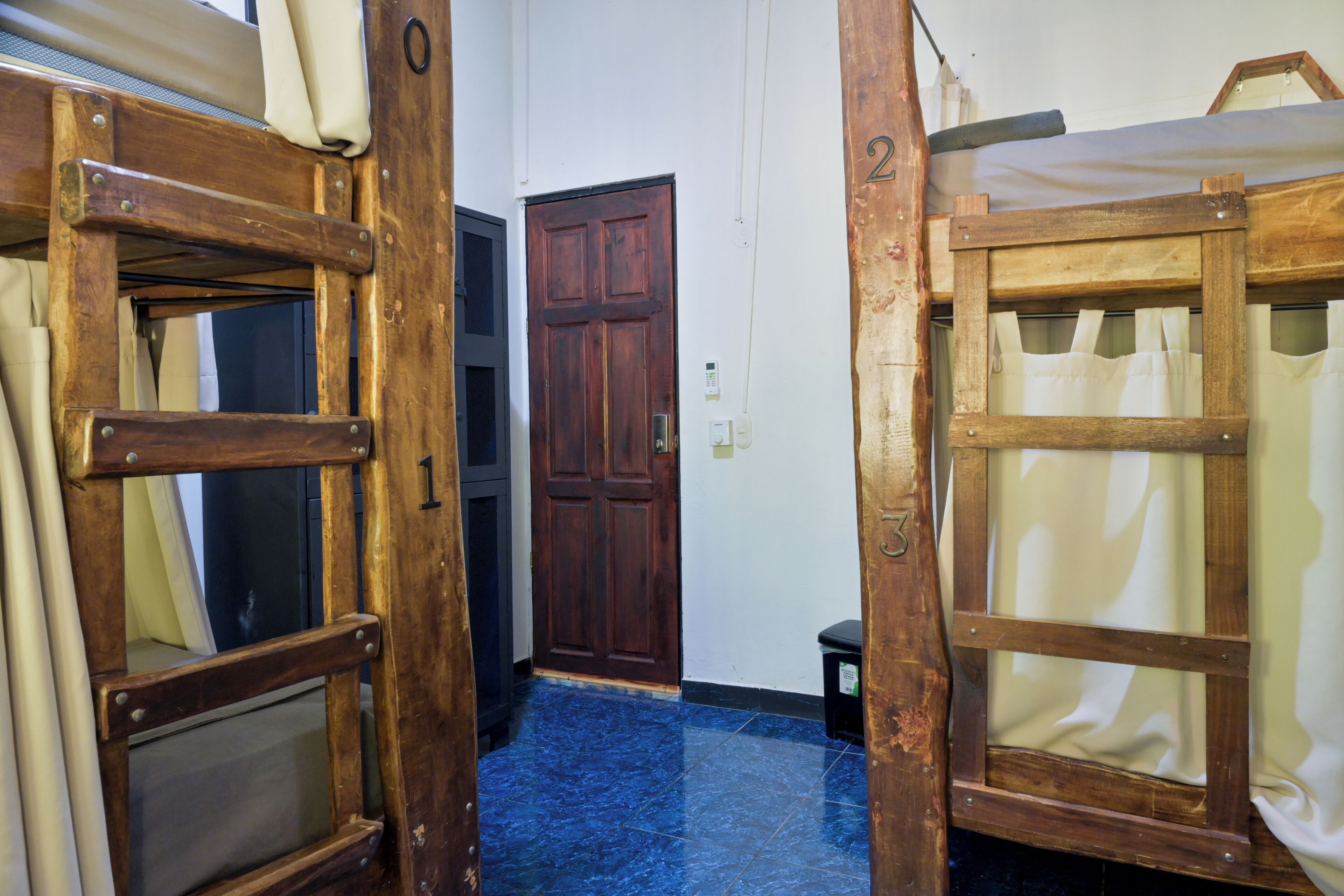 Un pasillo estrecho con puertas de madera y suelo de baldosas azules.