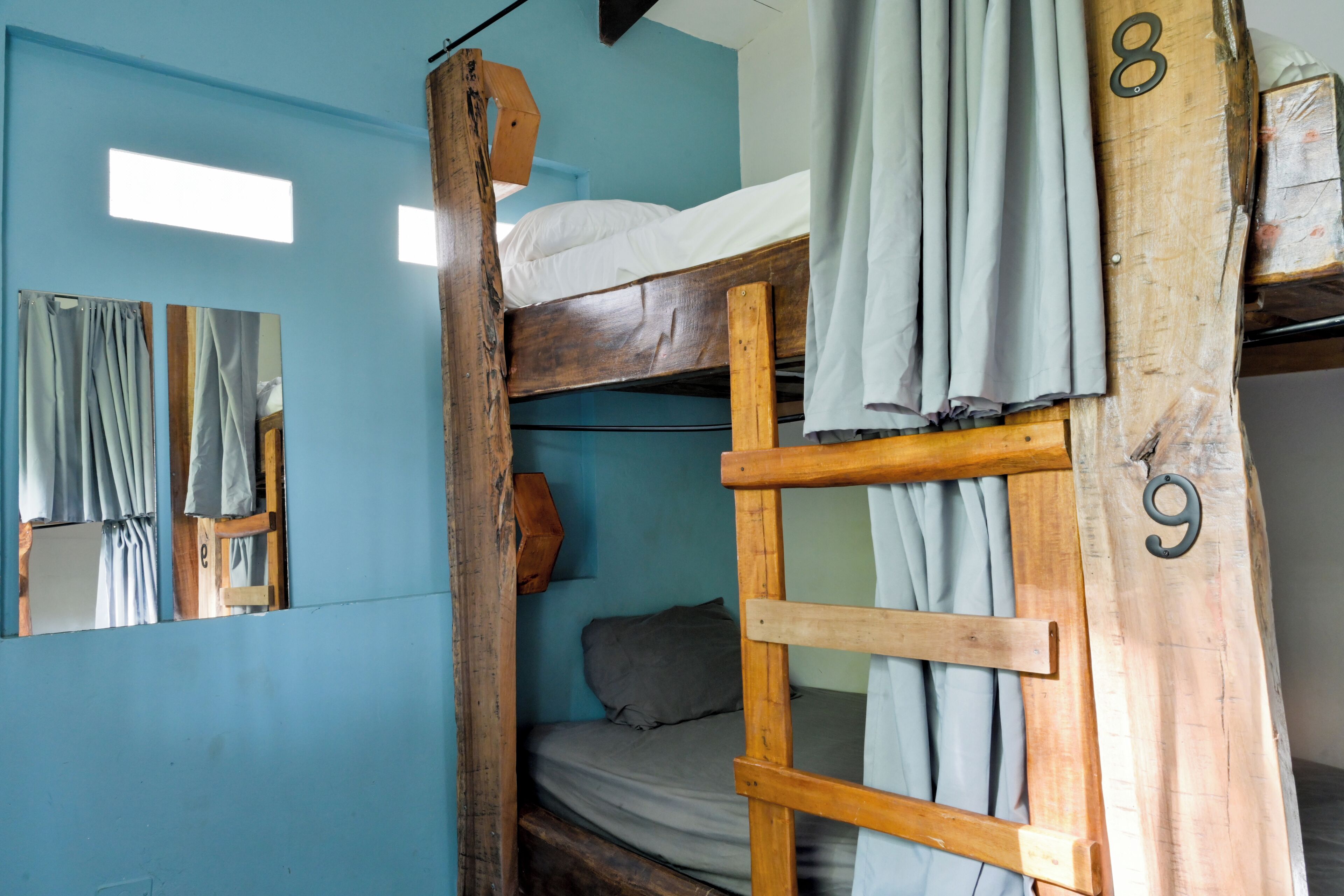Una cama litera con los números 8 y 9, cabecero de madera y un espejo.
