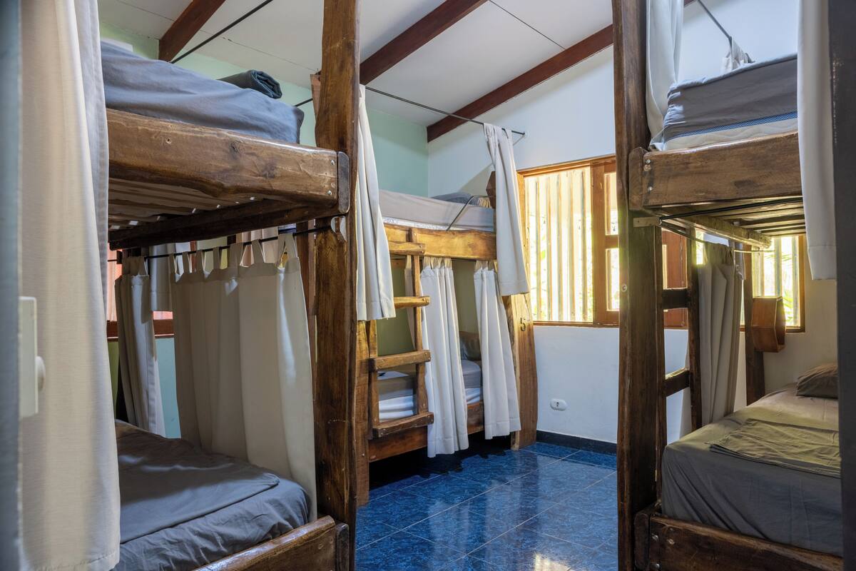 Ein Zimmer mit Etagenbetten, Holzbalken und Steinboden.