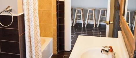 Embrace luxury in this chic bathroom: a stylish sink, a gleaming mirror, and a bathtub accented by a charming ladder in the corner. Modern amenities harmonize, promising a stay where sophistication and comfort converge seamlessly.