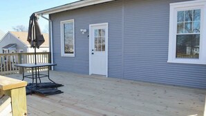 Une terrasse avec une table et des chaises, une porte et une fenêtre.