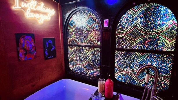 A room with a neon sign, two framed artworks, a bathtub, and mosaic windows. - Spend an evening w Trolley Parton! #Love #IndoorProjector #Vibes #Renew (Doyle)