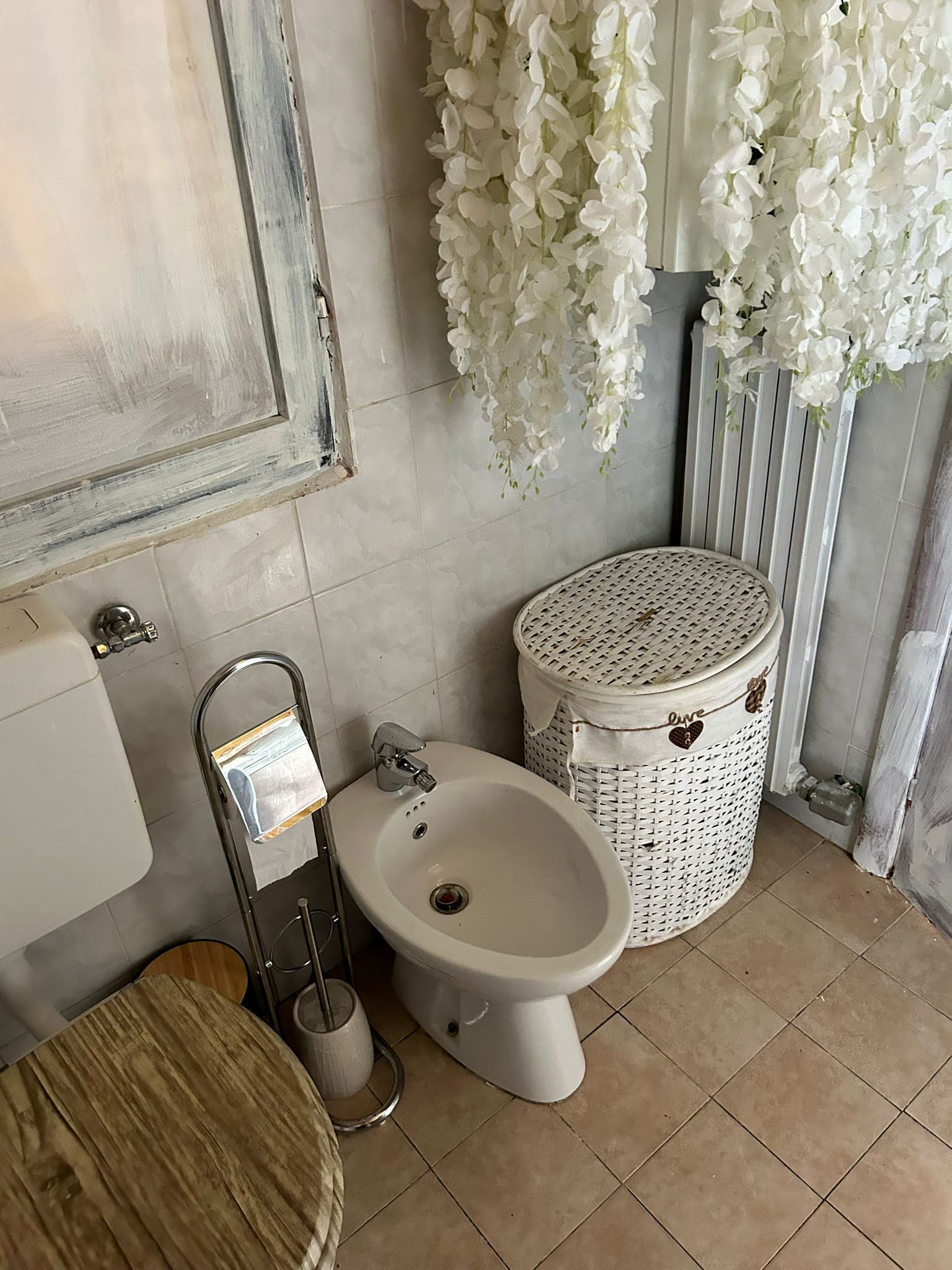 A bathroom with a white sink, a bidet, a toilet, and a wicker trash bin.