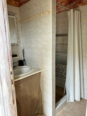 Een badkamer met een wastafel, spiegel en douchehoek.