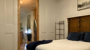A bedroom with a large bed, a wooden headboard, a ceiling fan, and a painting on the wall.