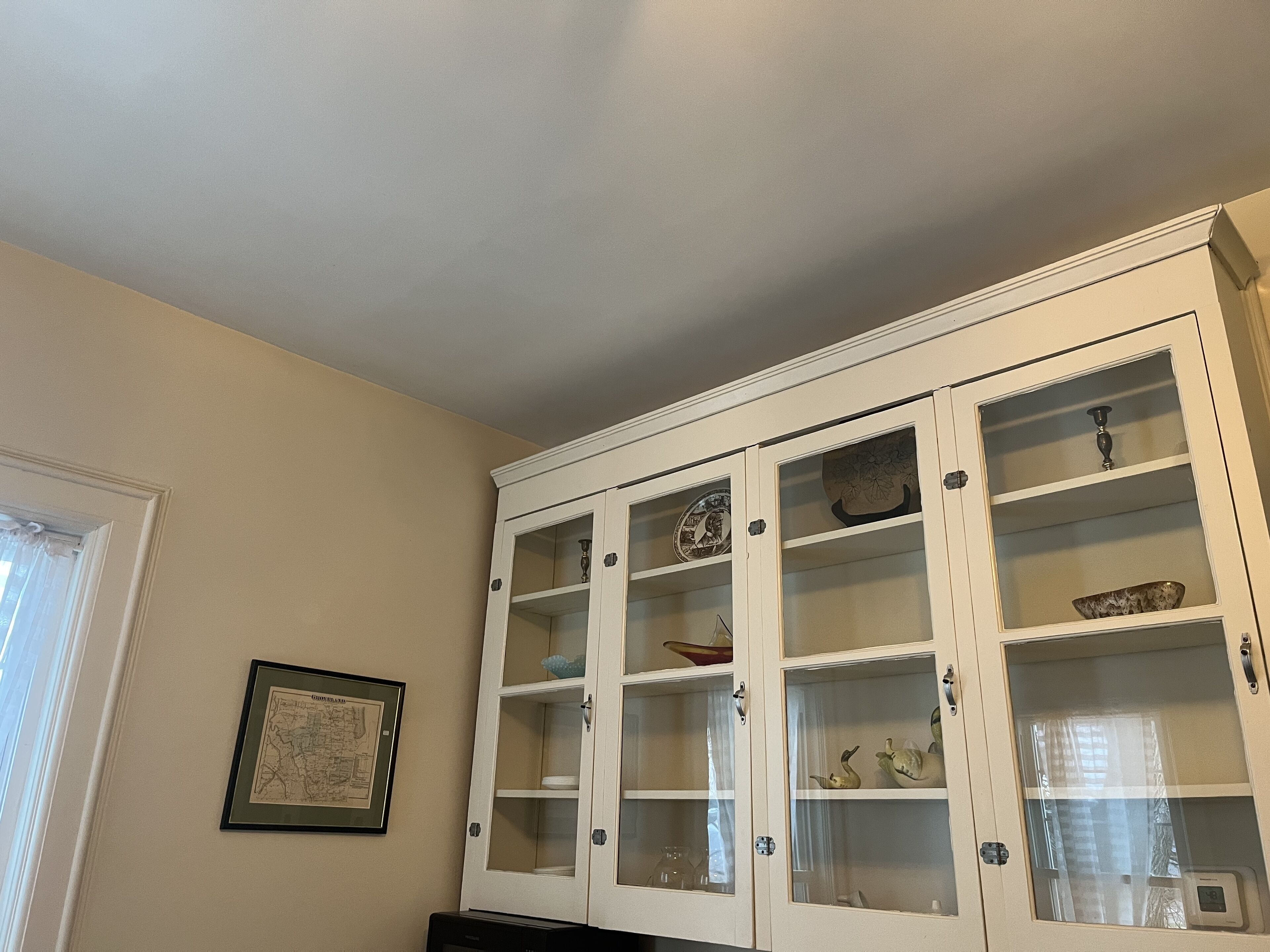 Een kamer met een witte kast voorzien van glazen planken met diverse spullen.