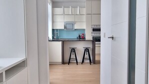 Une cuisine moderne avec des meubles blancs, un plan de travail bleu et un tabouret noir.