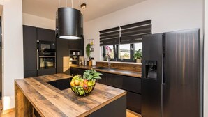 A modern kitchen with a wooden island, stainless steel appliances, and a large window with blinds. - Villa Summer Dream - luxury and adventure by MyWaycation (Vrana)