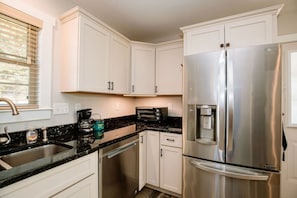 A modern kitchen with white cabinets, stainless steel appliances, a built-in dishwasher, and a coffee maker. - Mountain Apple Orchard Cottage| Views & Farm Charm (Flat Rock)