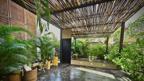An indoor garden with a concrete floor, bamboo ceiling, and various potted plants. - Bohemian Avant-garde 2BR Apartment (Tulum)