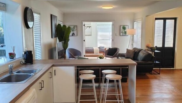 A modern kitchen with a central island, bar stools, and a dining area with a sofa.