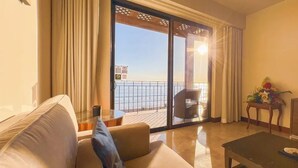 Un salon avec un canapé, une table basse et une vue sur la mer, visible à travers une porte-fenêtre coulissante.