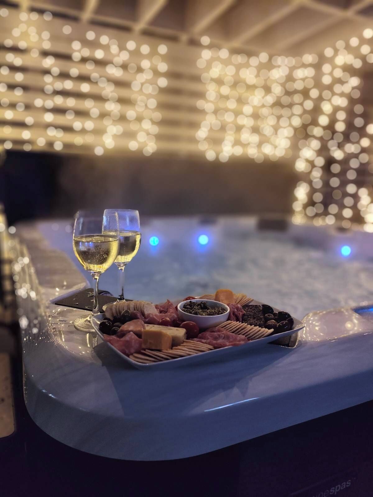 Un bain à remous avec un plateau de collations et deux verres de vin blanc.