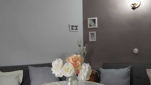 Una sala de estar con una mesa redonda, sofás grises y un techo decorativo.
