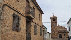 Un edificio de piedra con una torre de campanas, una entrada porticada y una calle empedrada.