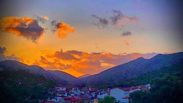 Un pueblo enclavado en un valle, con montañas al fondo, bajo un cielo al atardecer.