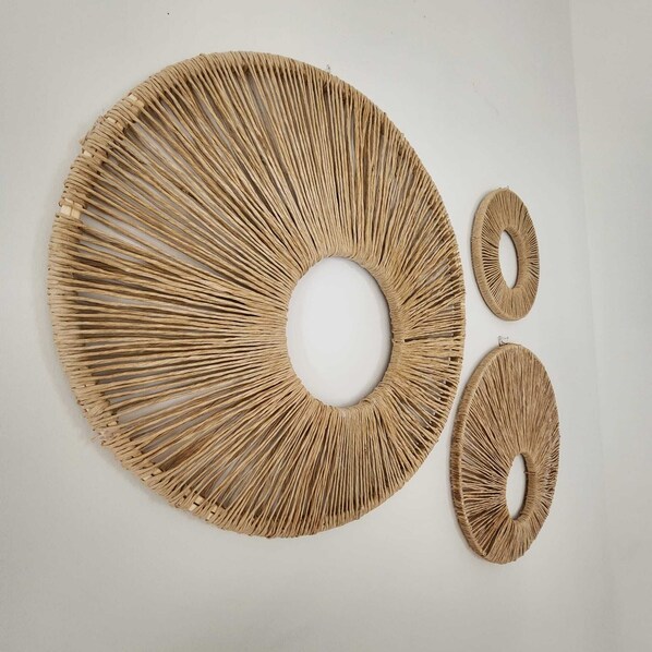 A circular woven wall hanging with a central hole, accompanied by two smaller circular pieces.