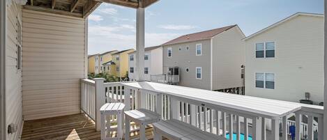 A covered deck with white railings and a pool.