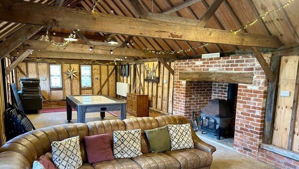 A cozy room with a leather sofa, a pool table, and a brick fireplace. - Delightful rural country cottage, Great for families and groups, large garden and a big hot tub! (Beccles)