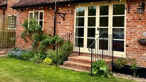 A brick house with a tiled roof, a front porch with steps, and a garden with various plants. - Delightful rural country cottage, Great for families and groups, large garden and a big hot tub! (Beccles)