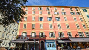A multi-story building with a red facade, multiple windows, and storefronts at the ground level. - 3 bedroom cozy apartment in Ajaccio (Ajaccio)