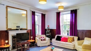 A living room with a fireplace, a television, a Christmas tree, and two sofas. - 9 bedroom accommodation in Kirknewton, near Edinburgh (Kirknewton, near Edinburgh)