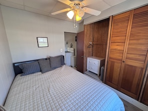 A bedroom with a bed, a wardrobe, a nightstand, a ceiling fan, and a framed picture on the wall. - 1 Block to the Beach! Firepit, 2 Bikes, Sleeps 4 (Two Rivers)
