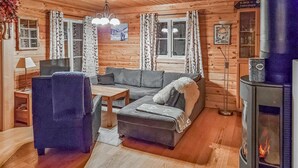 Tunnelmallinen hirsihuvilan sisustus, jossa on sohva, nojatuoli, puupöytä ja takka.