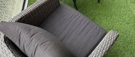 A balcony with wicker furniture, including a sofa and chairs, and a small round table.