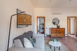 Ein Wohnzimmer mit einer Couch, einem runden Couchtisch, einer Holzkommode und einer Stehlampe.