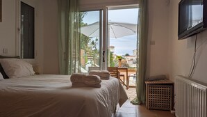 A bedroom with a bed, a TV, a radiator, and a view of the outdoors. - Romantic High-End Pool 3-bedroom villa in Peyia, Cyprus (Peyia)